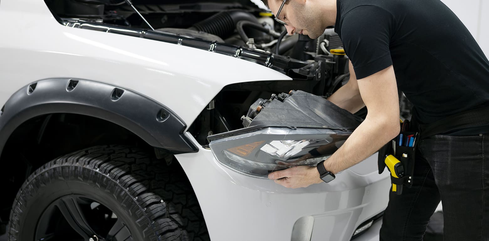 Automobile technician replacing headlights of car
