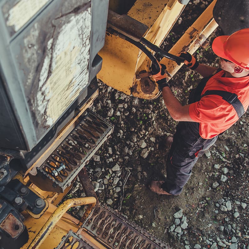 construction worker fixing equipment Technician working on construction equipment diagnostics