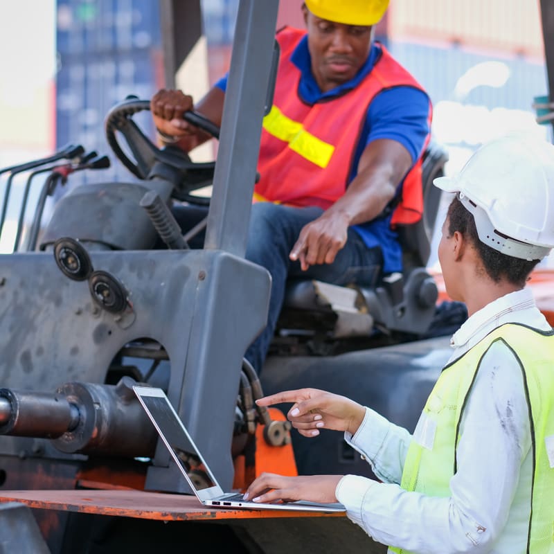 African,American,Technician,Worker,Woman,Use,Laptop,To,Discuss,With diagnosing fault codes on a forklift inside a warehouse